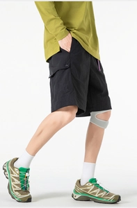 Detail of black tactical cargo shorts featuring side accordion pockets and purple accents