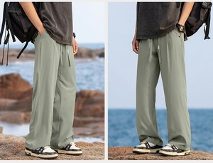 Sage green hiking trousers with drawstring waist shown in seaside lifestyle setting