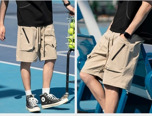 Detail of khaki cargo shorts showing drawstring waist and black zipper side pockets on court