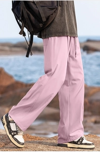 Detail of pink straight-leg leisure trousers with drawstring waist on coastal rocks