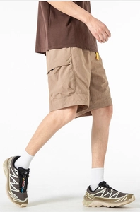 Detail view of khaki cargo shorts with side pockets and bright yellow drawstring details