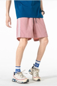 Dettaglio dei pantaloncini sportivi grigio-rosa con strisce laterali bianche e coulisse