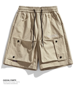 Detail of khaki cargo shorts showing elastic waistband with drawstring and large flap pockets