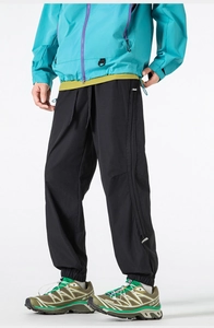 Detail of loose fit hiking trousers with elastic drawstring hem and durable black fabric