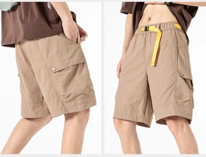 Detail of khaki cargo shorts featuring a contrast yellow belt and snap pocket closure