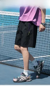 Men's ice-skin fabric shorts in black, styled with sneakers on an outdoor tennis court