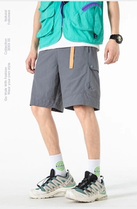 Detailed view of gray functional cargo shorts featuring a vibrant orange waist belt detail