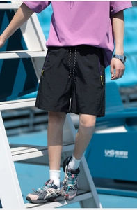 Detail of black quick-dry tech shorts with purple zipper pockets and yellow pull tabs