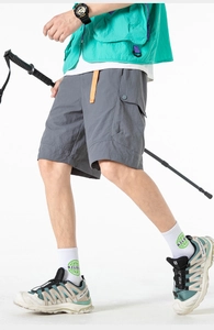 Detail showing side cargo flap pocket with snap button on dark grey outdoor shorts