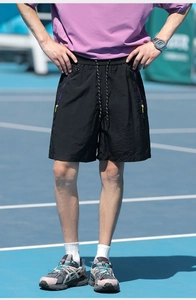 Close-up of black shorts featuring purple zipper pockets and yellow pull tabs on the side