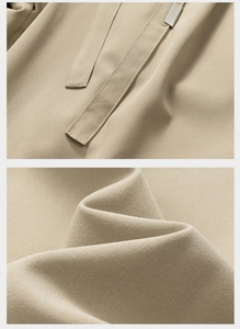 Detail of light khaki twill fabric pants with adjustable drawstrings and metal tips