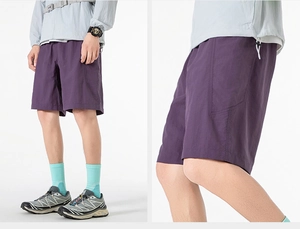 Detail of dark purple cargo shorts with side pockets and adjustable drawstring hem