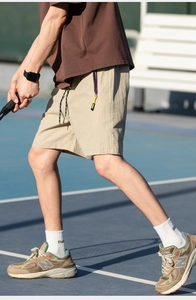 Detail of light khaki quick-dry cargo shorts with adjustable drawstring and purple accents
