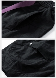 Detail of black ice skin shorts with elastic waist and distinctive purple woven belt