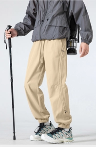 Detail of khaki outdoor hiking pants featuring elastic drawstring waist and side zippers