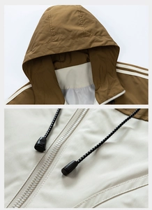 Dettaglio della giacca a vento color-block con zip bianca e trama del tessuto marrone