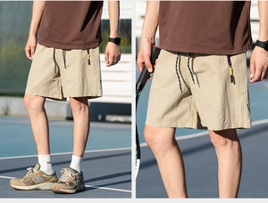 Detail of khaki techwear shorts featuring zipper pocket with purple trim and drawstring