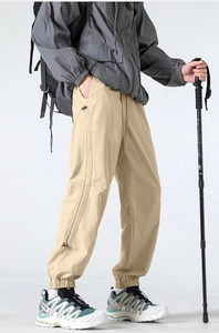 Detail view of khaki outdoor cargo pants with elastic cuffs and side zipper pocket