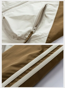 Dettaglio giacca outdoor con tasca a zip e strisce a contrasto bianco crema