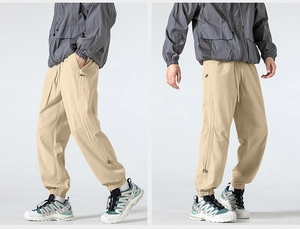 Detail view of khaki outdoor hiking pants with side zippers and elastic waistband