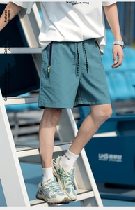 Detail view of teal athletic shorts featuring purple zipper pockets and yellow accents