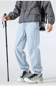 Detail view of light blue outdoor hiking pants featuring side zipper pockets and elastic cuffs