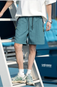 Detail of teal quick-dry athletic shorts with drawstring waist and contrast zipper pocket