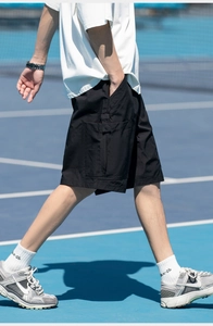 Detail of black utility cargo shorts featuring side pockets and webbed straps in motion
