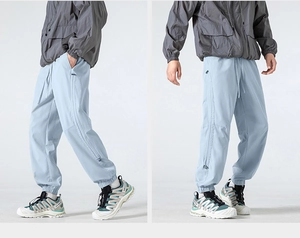 Detail view of light blue techwear joggers with elastic waistband and drawstring detail