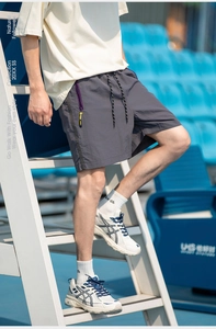 Detail of dark grey tech shorts featuring a purple taped zipper and yellow accents