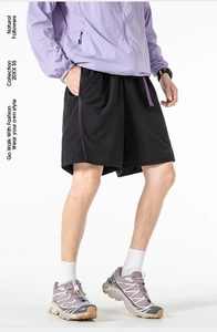 Detail of black quick-dry utility shorts featuring purple drawstring and loose fit design