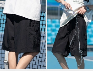 Detail of waterproof men's black cargo shorts showing water-resistant fabric in action