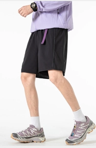 Close-up of black quick-dry outdoor shorts with purple webbing detail on model