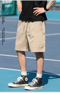 Detail view of khaki cargo shorts featuring large side pockets and drawstring waist design
