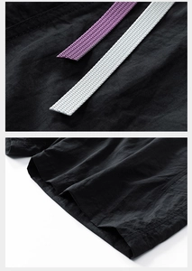 Detail view of black technical shorts with purple and white woven drawstrings and fine stitching