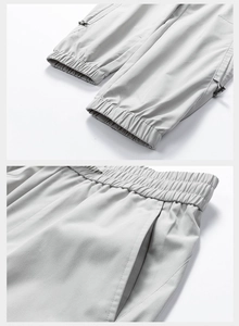 Detail of grey camping pants showing elastic drawstring waist and side zipper pockets