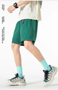Detail of dark green cargo shorts featuring drawstring elastic waist and side stripes