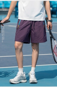 Detail of purple quick-dry athletic shorts with vibrant yellow zipper pockets for men