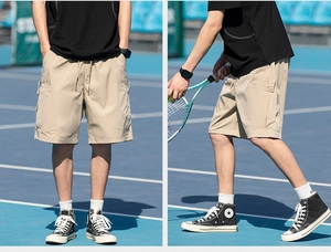 Detail view of khaki cargo shorts featuring large side pockets and elastic drawstring waist