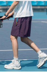 Detail of purple quick-dry shorts with bright blue zipper pocket on tennis court