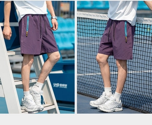 Detail view of purple sports shorts with a blue zipper pocket and drawstring on tennis court