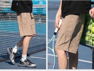 Dettaglio dei pantaloncini sportivi kaki in tessuto leggero su un campo da tennis