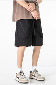 Dettaglio dei pantaloncini cargo neri con tasche laterali a zip e vita con coulisse