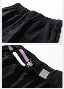 Dettaglio della vita elastica con cinturino intrecciato tricolore su pantaloncini techwear neri