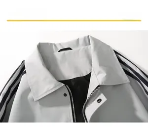 Detail of light grey jacket neckline with black shoulder stripes and metal snaps