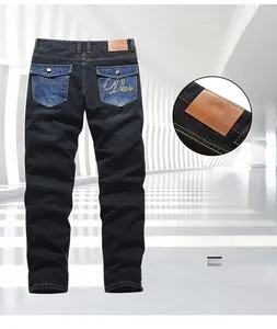 Detailansicht dunkler Jeans mit braunem Lederlogo-Patch und goldener Stickerei auf der Tasche