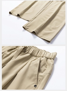 Detail of khaki hiking trousers showing elastic waistband and metallic rivet pocket accents