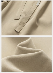 Close-up of beige quick-dry fabric showing fine stitching and silver metal drawcord tips