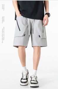 Dettaglio dei pantaloncini cargo grigio chiaro con elastico in vita e tasche nere con zip