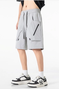 Dettaglio dei pantaloncini cargo grigi con vita elastica, coulisse e tasca con zip